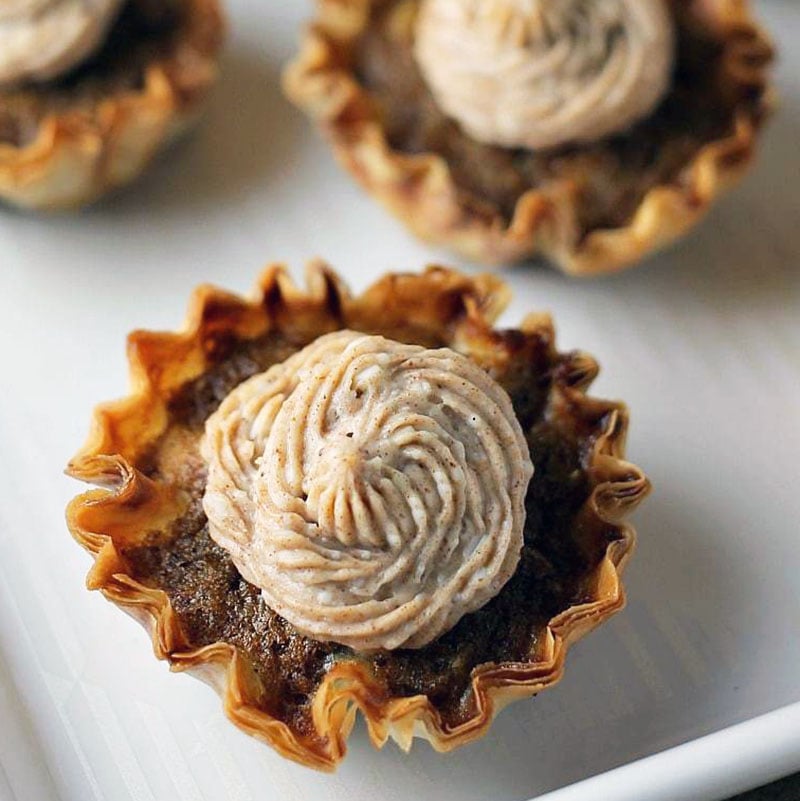 Mini Sweet Potato Pies with Cinnamon Cream Cheese Frosting are super easy to make but look fancy. Impress your guests with these bite sized treats! | www.persnicketyplates.com #pie #sweetpotatopie #thanksgiving #minidessert #dessert closeup of mini sweet potato pie with cinnamon cream cheese frosting