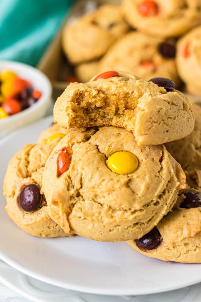 stack of reese's pieces cookies with a bite missing from one.
