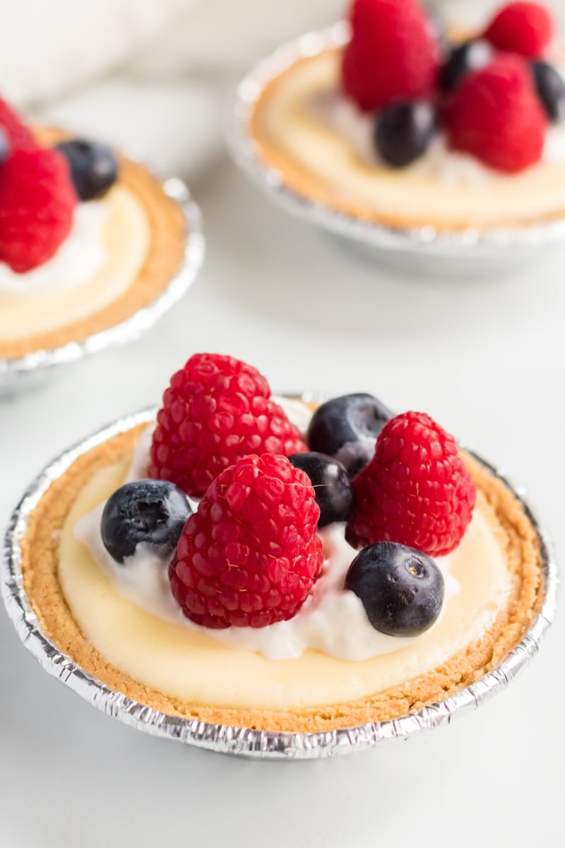 three mini cheesecake topped with raspberries & blueberries