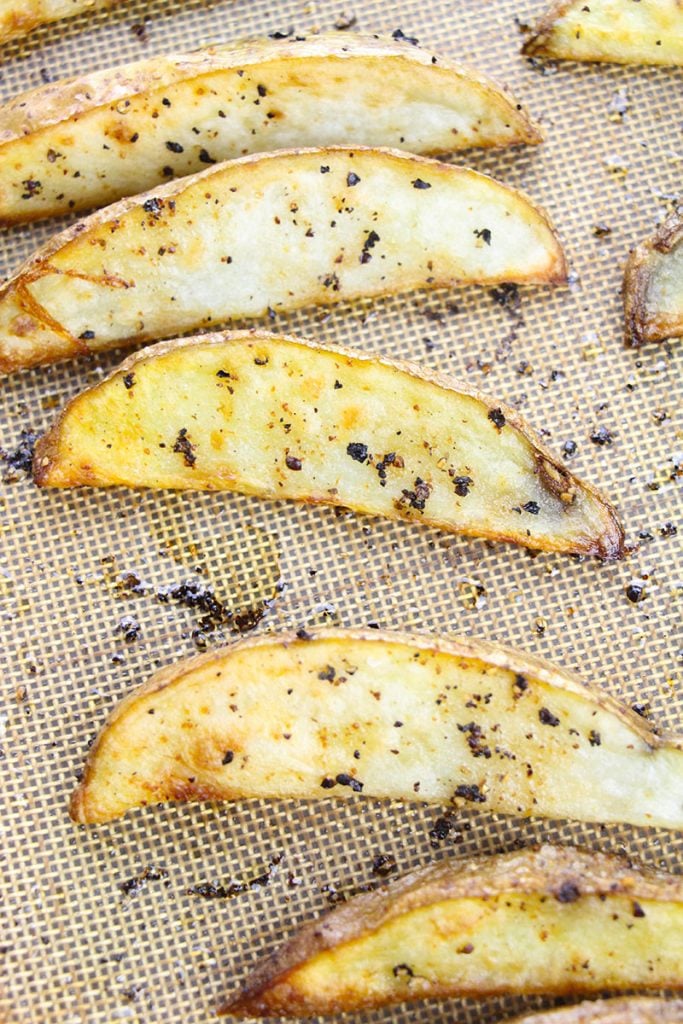overhead shot of seasoned potato wedges on a baking sheet.