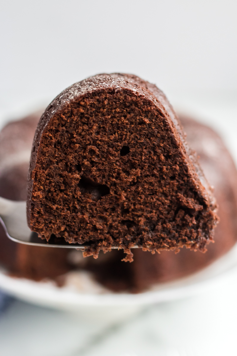 This rich, dense Sour Cream Chocolate Bundt Cake is a copycat of the famous Williams Sonoma recipe. Perfect for those chocolate cravings! | www.persnicketyplates.com slice of williams sonoma sour cream chocolate bundt cake on serving knife