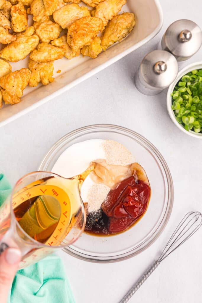 vinegar pouring into a bowl of sauce ingredients.