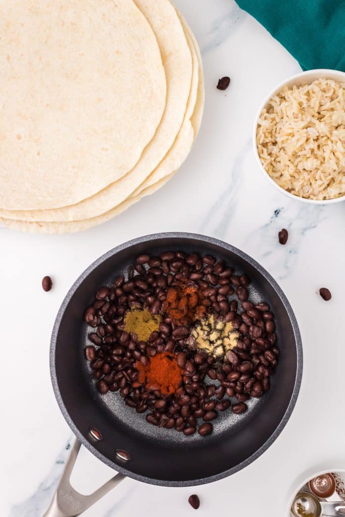 overhead shot of black beans and seasonings in a saucepan.