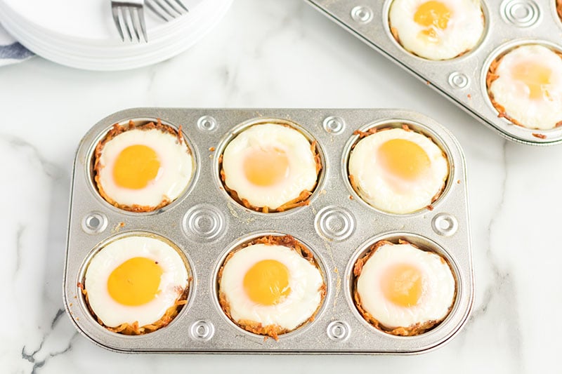 Bird's Nest Breakfast Cups are a fun way to eat eggs and hash browns for breakfast. These baked egg cups combine hash browns and cheese to form a "nest" and are topped with an egg. | www.persnicketyplates.com bird's nest breakfast cups in a muffin tin