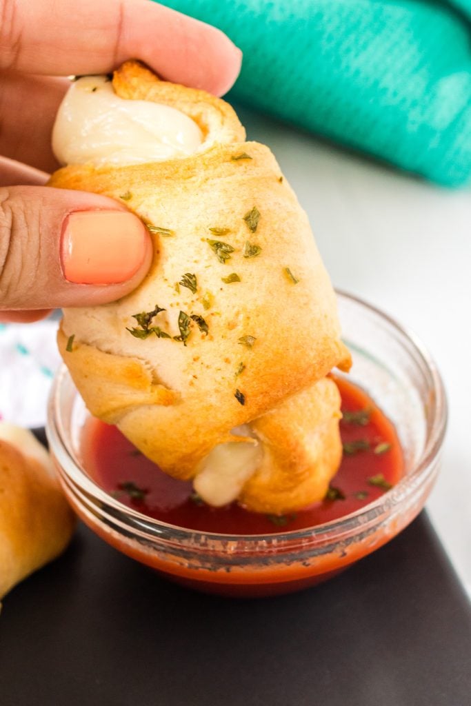 pizza roll being dipped into marinara sauce.
