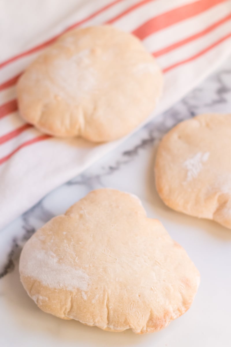 three homemade pita breads on a marble surface  