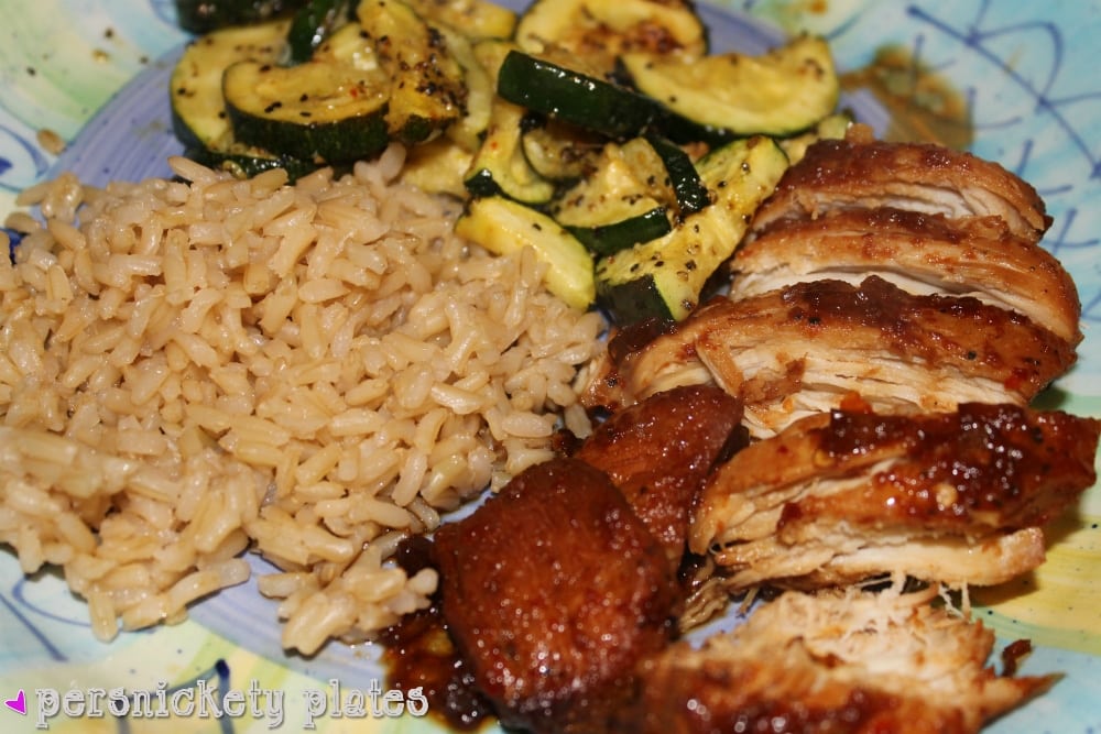 plated bourbon chicken with rice and zucchini overhead shot of bourbon chicken, brown rice, and zucchini on a dinner plate.