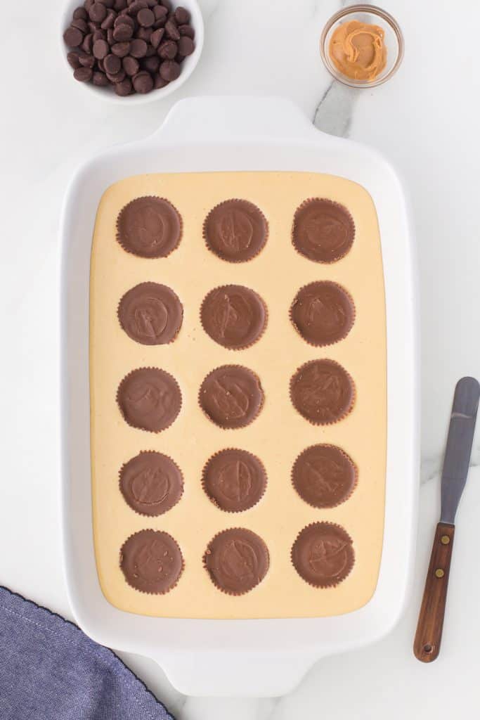 reese's peanut butter cups sticking into cheesecake batter.