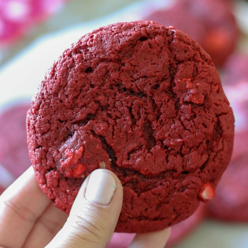 single red velvet cream cheese swirl cookie being held up 