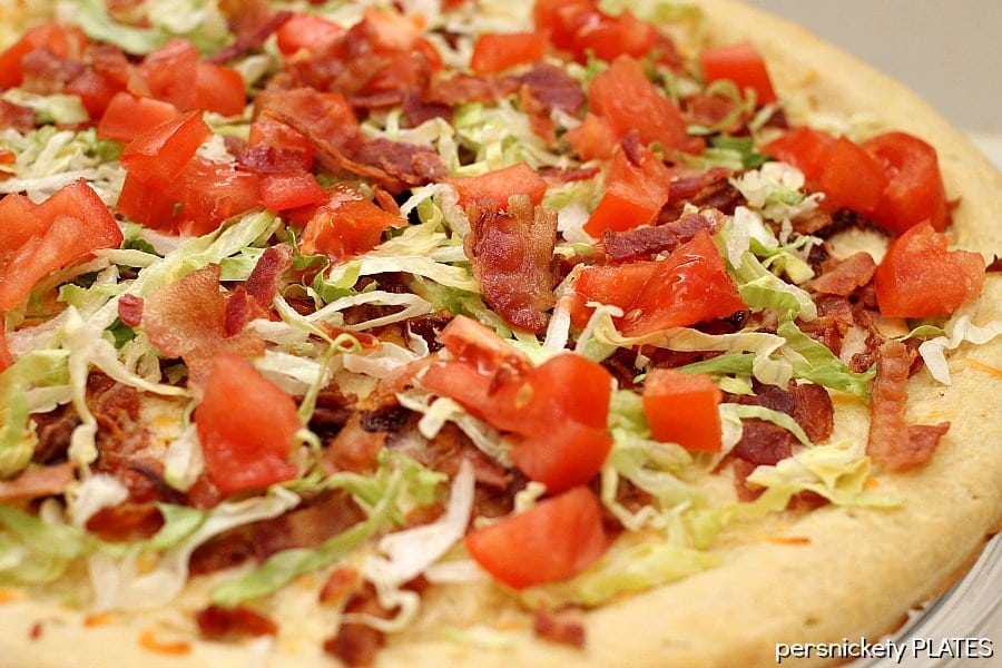 This BLT Pizza is semi-homemade and topped with cheese, bacon, lettuce, and tomatoes then drizzled with ranch dressing - a super easy meal for pizza night at home! | www.persnicketyplates.com close up of blt pizza with fresh lettuce & tomatoes on top