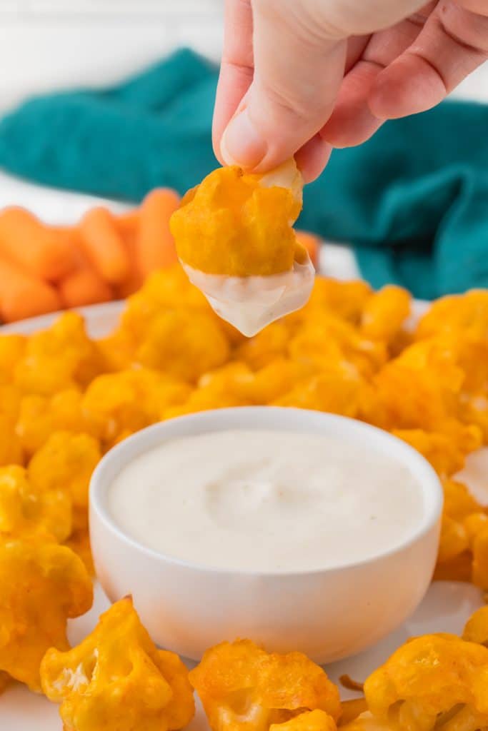 hand dipping buffalo cauliflower in ranch.