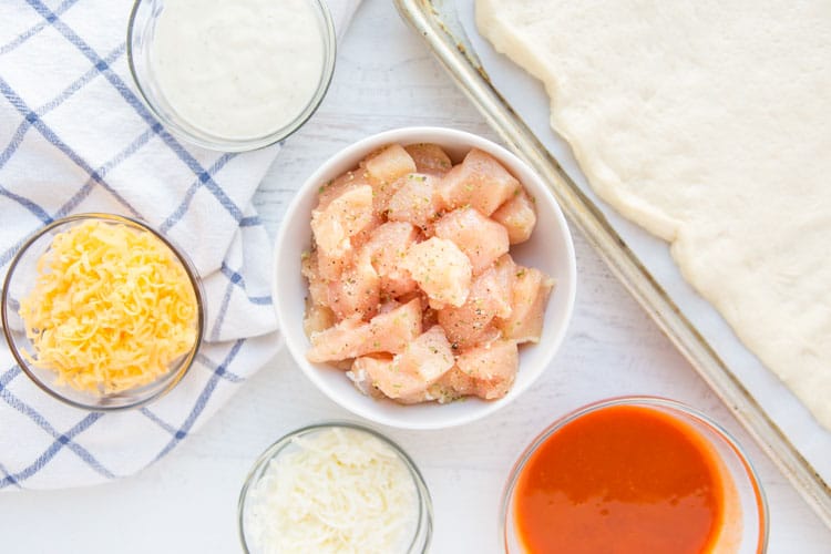 Buffalo Chicken Bread is easy to make at home & better than take-out! Stuffed bread recipes make the perfect weeknight dinner, and they're great for serving at parties or as game day snack food. This easy stuffed bread recipe starts with pizza dough then is filled with spicy Buffalo chicken and cheese. SO delicious! | www.persnicketyplates.com chicken, cheeses, buffalo sauce mise en place