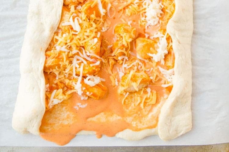 Buffalo Chicken Bread is easy to make at home & better than take-out! Stuffed bread recipes make the perfect weeknight dinner, and they're great for serving at parties or as game day snack food. This easy stuffed bread recipe starts with pizza dough then is filled with spicy Buffalo chicken and cheese. SO delicious! | www.persnicketyplates.com rolling of buffalo chicken bread on dough