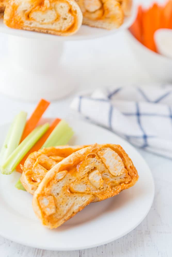 Buffalo Chicken Bread is easy to make at home & better than take-out! Stuffed bread recipes make the perfect weeknight dinner, and they're great for serving at parties or as game day snack food. This easy stuffed bread recipe starts with pizza dough then is filled with spicy Buffalo chicken and cheese. SO delicious! | www.persnicketyplates.com slice of buffalo chicken bread on white plate