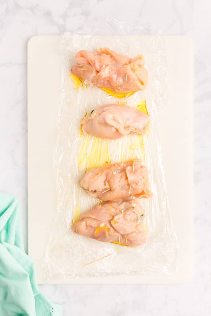 rolled raw chicken breasts laying on a cutting board.