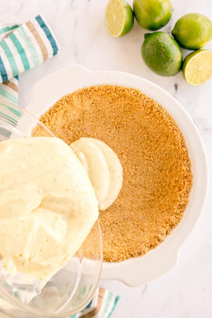 pouring filling into a graham cracker pie crust.