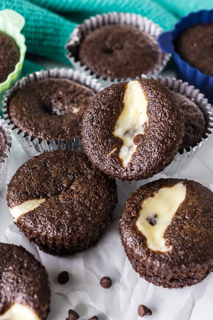 A close-up of freshly baked chocolate cupcakes with creamy cheesecake filling peeking through the tops.