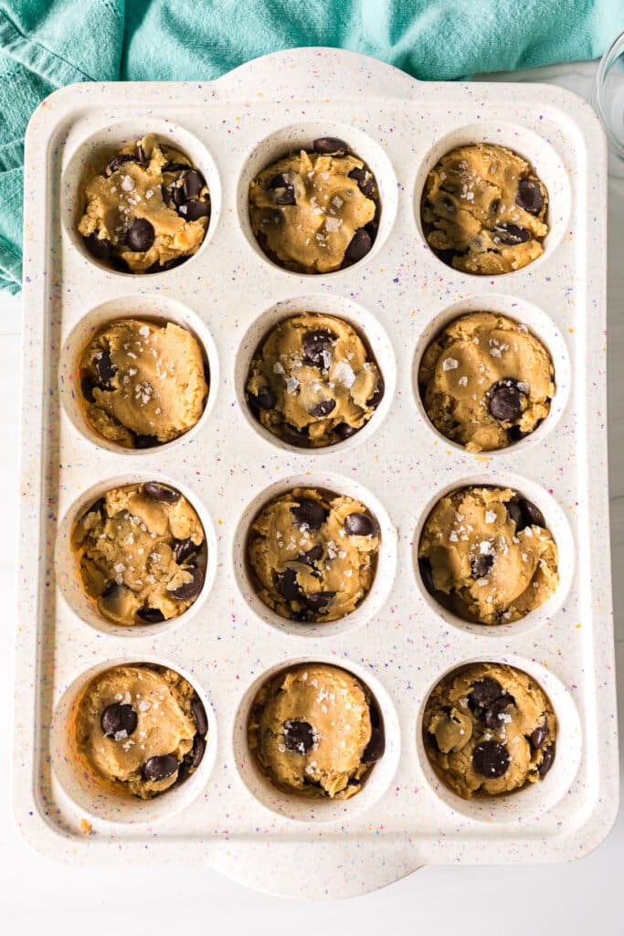 overhead shot of chocolate chip cookie dough in a muffin pan.