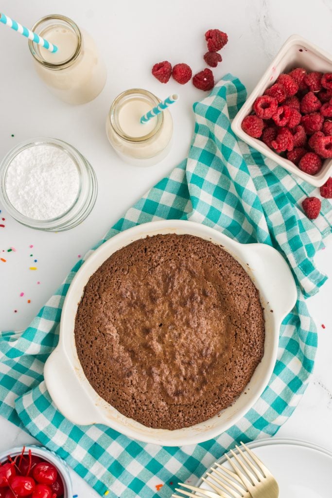 overhead shot of fudge pie surrounded by berries and glasses of milk.