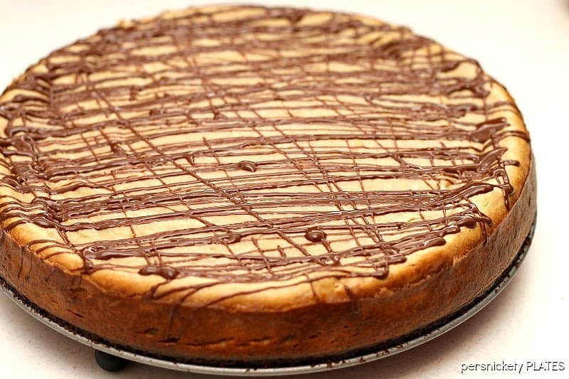 Brownie Bottom Peanut Butter Cheesecake drizzled with chocolate on springform pan Brownie Bottom Peanut Butter Cheesecake has a layer of chewy brownie topped with a creamy peanut butter cheesecake and drizzled with rich chocolate. | www.persnicketyplates.com #cheesecake #peanutbutter #brownie #dessert