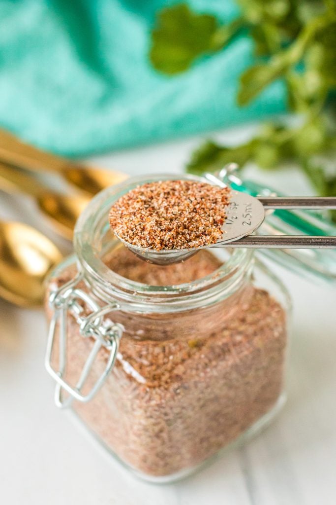 teaspoon scooping taco seasoning from a glass jar