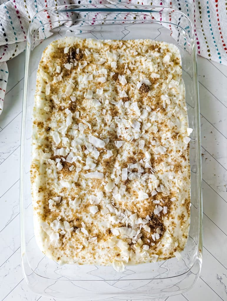 coconut flakes and brown sugar sprinkled on a 9x13 baking dish of cake batter.