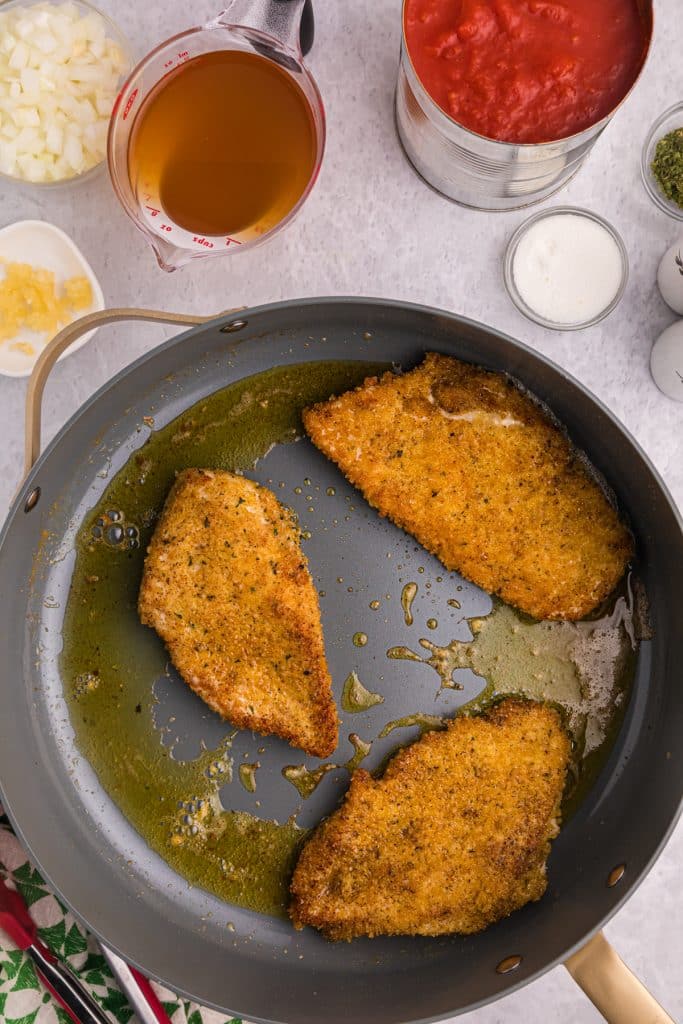 breaded chicken cutlets in a skillet.