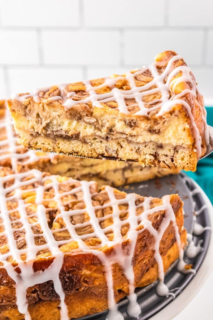 slice of cinnamon roll cheesecake being lifted from the cake.