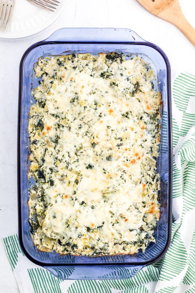 overhead shot of spinach artichoke chicken casserole in a blue baking dish.