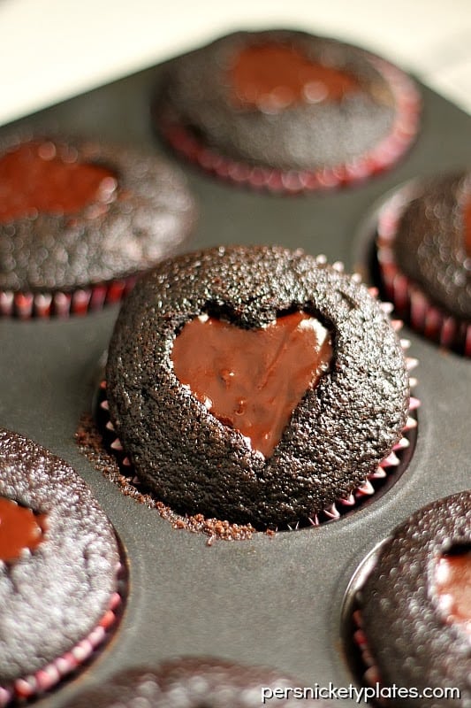Dark chocolate cupcakes with a heart shaped cut-out filled with chocolate ganache and topped with sprinkles. Perfect for Valentine's Day!