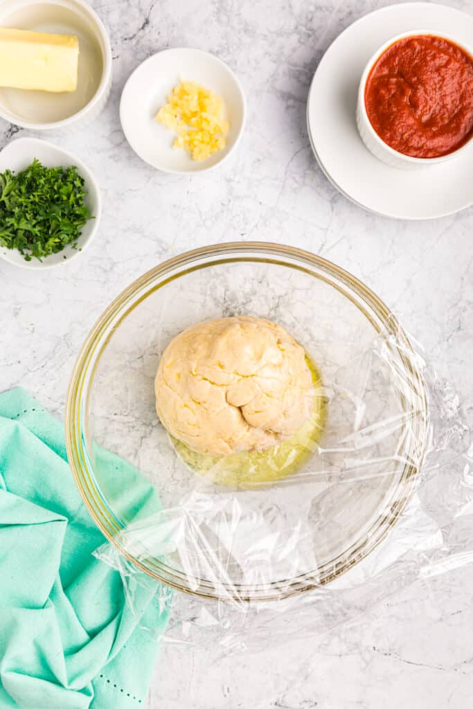 ball of dough proofing in a glass bowl.