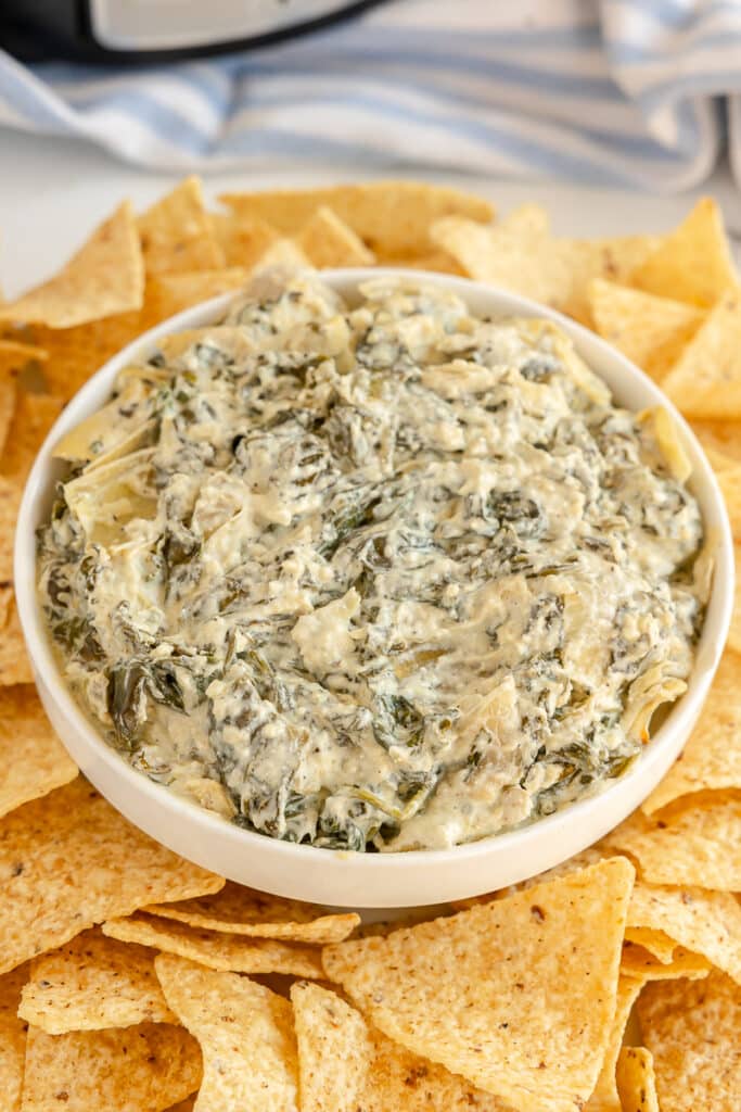 bowl of spinach artichoke dip surrounded by tortilla chips.