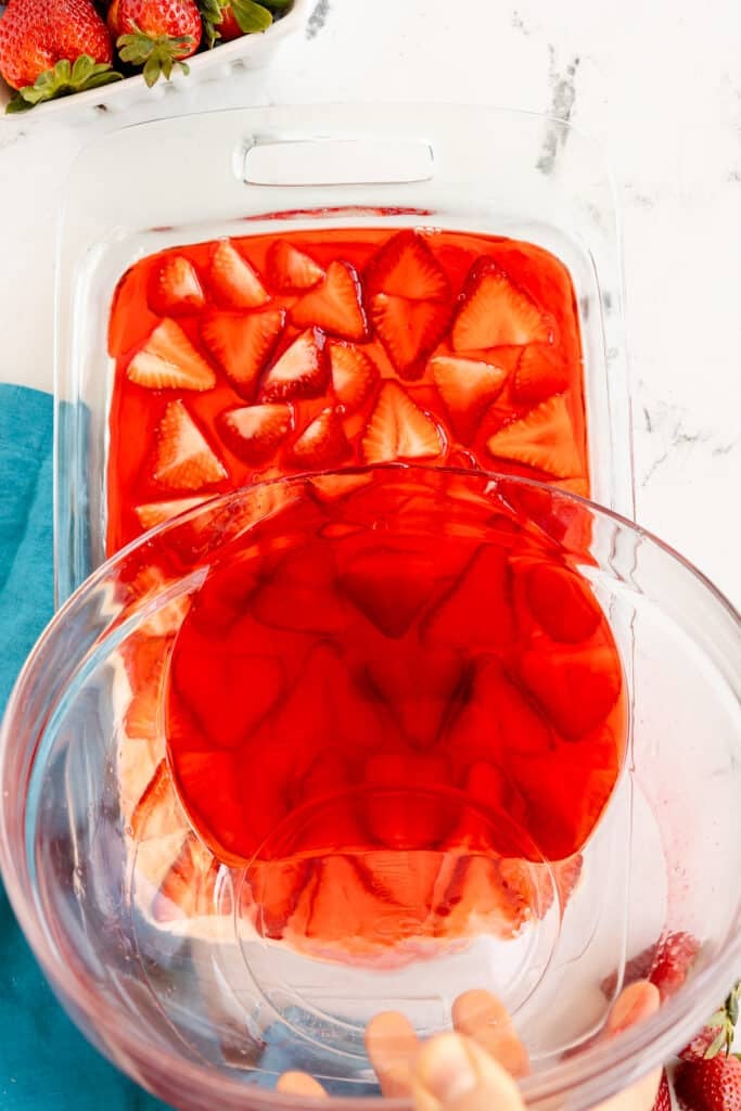 strawberry gelatin being poured into a baking dish.