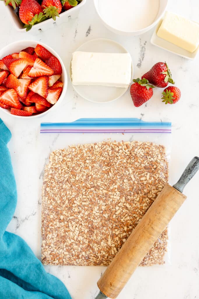 pretzels being crushed in a zip top bag with a rolling pin.