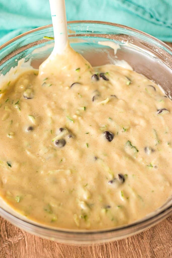 chocolate chip zucchini muffin batter in a mixing bowl with a spatula.
