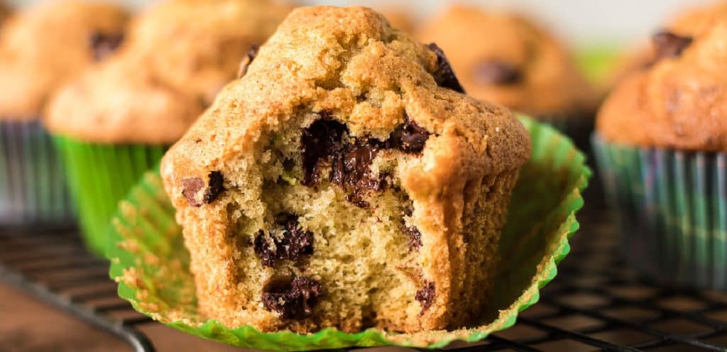 side view of a zucchini muffin with a bite missing and melty chocolate chips.