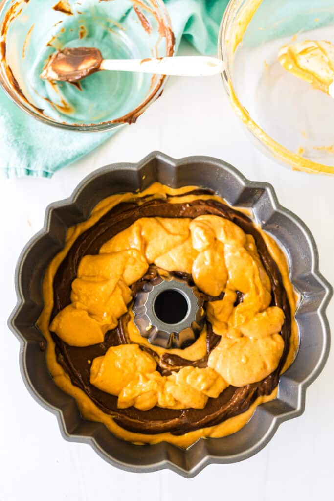 layered chocolate and pumpkin cake batter in a bundt pan.