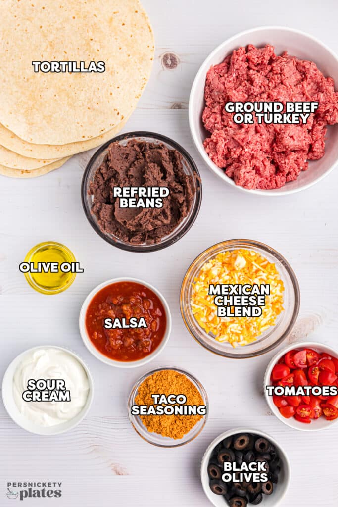 overhead shot of labeled ingredients laid out to make mexican pizzas.