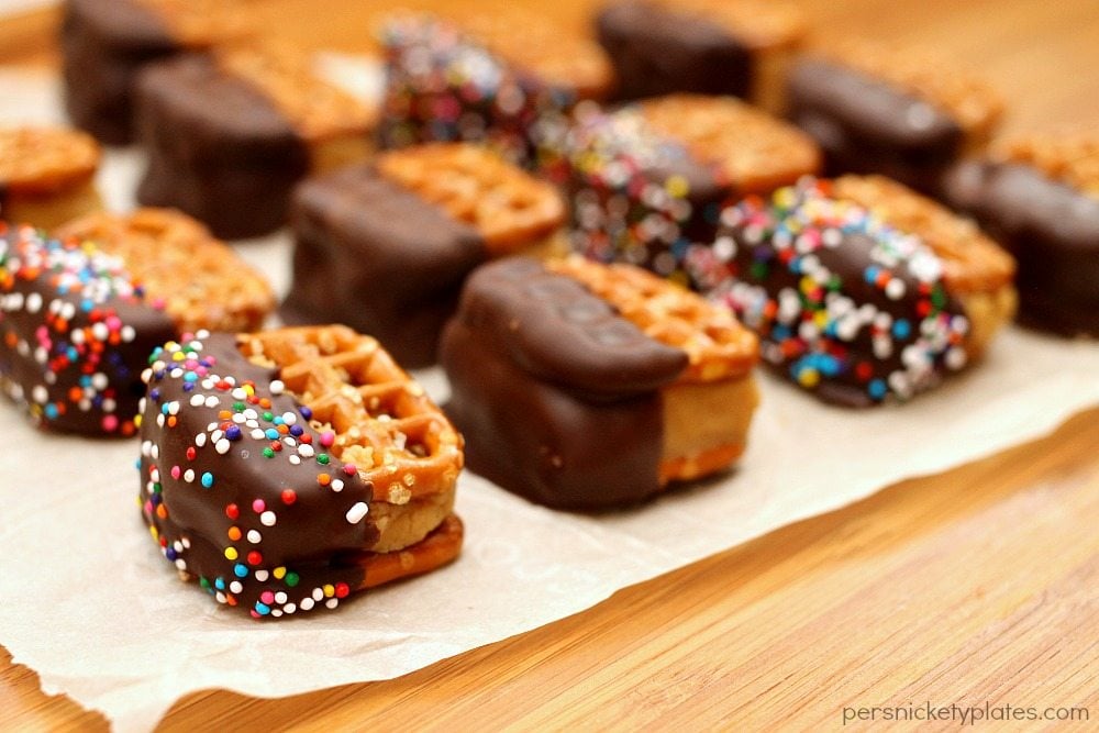 chocolate dipped peanut butter pretzel bites on parchment paper