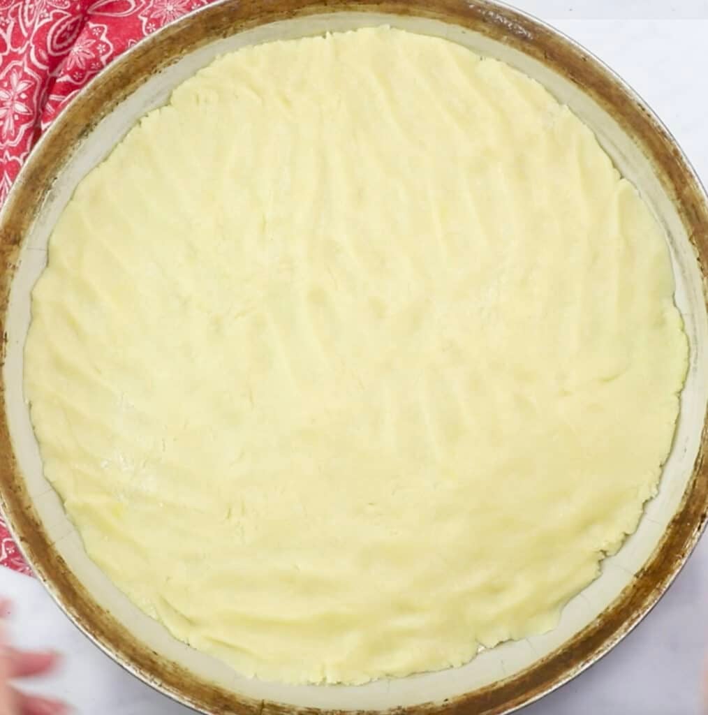 sugar cookie dough pressed onto a round baking sheet.