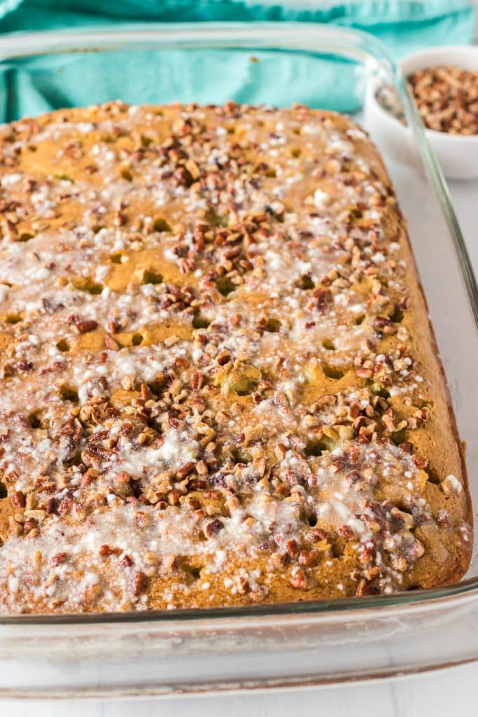 overhead shot of a poke cake topped with chopped pecans in a baking dish.