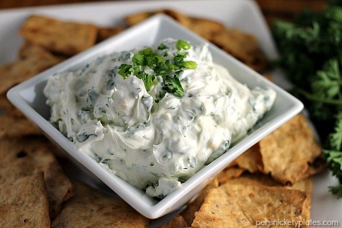 close up of garlic herb dip in square bowl