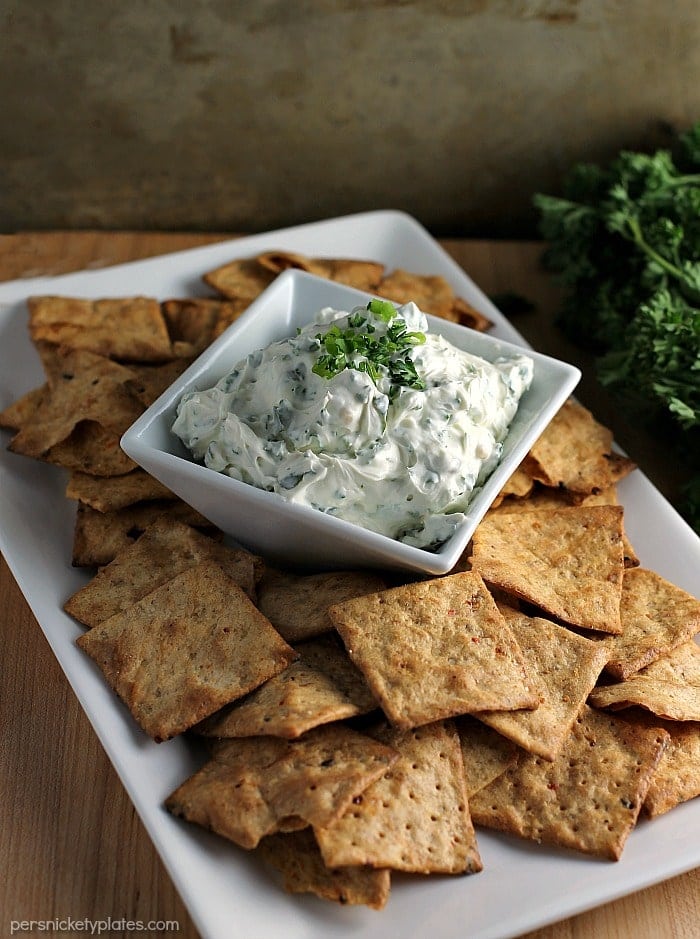 garlic herb dip surrounded by chips on white platter