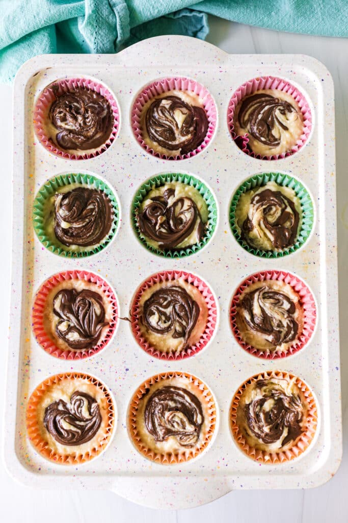 overhead shot of unbaked nutella swirl muffins in a cupcake pan.