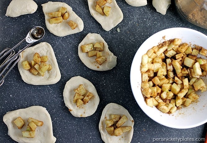 Apple Filled Pull Apart Bread is sticky and sweet and easy to make with the help of Rhodes Dinner Rolls! Pick your favorite fall apples and let your kids help you put together this simple dessert. | Persnickety Plates overhead shot of dough with sugared apples on top for Apple Filled Pull Apart Bread