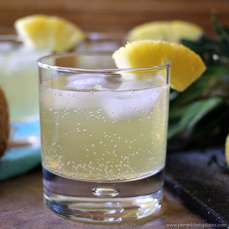 pineapple coconut cocktail in glass with pineapple garnish Skinny Pineapple Coconut Cocktail is a fizzy, low calorie drink that is perfect for summertime. | www.persnicketyplates.com