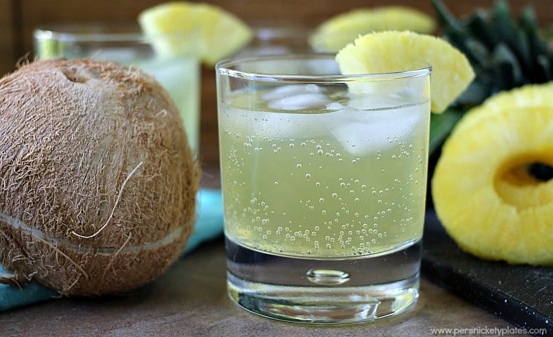 skinny pineapple coconut cocktail sitting next to a coconut Skinny Pineapple Coconut Cocktail is a fizzy, low calorie drink that is perfect for summertime. | www.persnicketyplates.com
