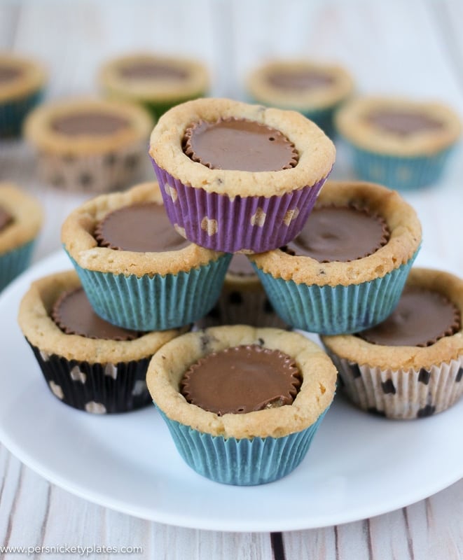 Chocolate Chip Peanut Butter Cookie Cups are only two ingredients and are ready in just 20 minutes. Perfect for a last minute bake sale, class treat, or craving! | www.persnicketyplates.com #easydessert #cookie #cookiecups #semihomemade #dessert pyramid of cookie cups stacked up with colorful wrappers