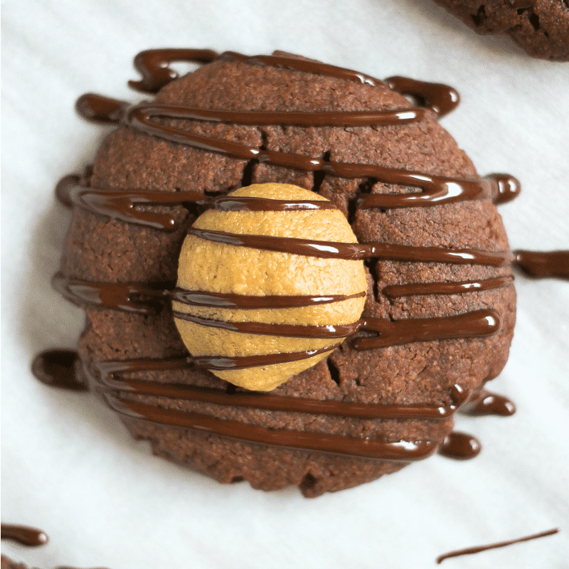 close up of chocolate cookie filled with peanut butter and drizzled with chocolate