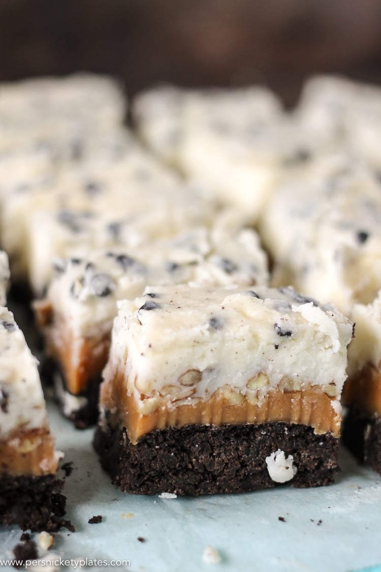 Cookies and Cream Caramel Layer Bars start with a layer of Pillsbury Cookies 'n Creme cookie dough, topped with a layer of caramel, chopped pecans, frosting, then finished with melted Cookies 'n Creme candy bars. I hope your sweet tooth is ready! rows of cookies and cream caramel layer bars